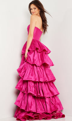 A woman models the Jovani 36619 Strapless Ruffled Prom Ball Gown, a floor-length hot pink dress, standing against a plain light background and looking over her shoulder at the camera.