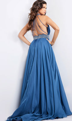 A woman stands against a plain light background, wearing the Long Prom Dress 36749 by Jovani—a flowing blue A-line gown with an open back, thin crisscross straps, and beaded details.