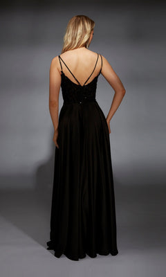 A woman stands facing away against a gray background, wearing the Aerie Couture 368 long black prom dress featuring an embellished bodice and thin straps.