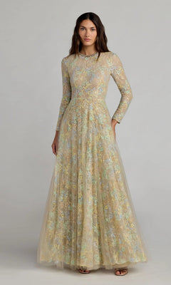 A woman wears the Mac Duggal 37016 long formal dress in Nude Multi, featuring long sleeves and a floor-length silhouette with a floral lace overlay, standing against a plain light background.