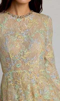 A person wearing the Mac Duggal 37016 long formal dress—a light beige nude lace gown adorned with pastel floral embroidery and a beaded neckline, shown from shoulders to waist—evokes refined elegance.