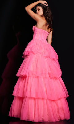 A woman poses with her back turned in a Jovani 37062 Strapless Long Ruffle Prom Ball Gown, featuring a corset-style bodice and tiered pink tulle skirt, set against a black background.