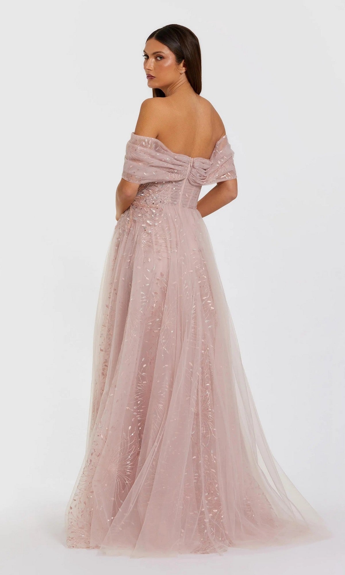 A woman poses with her back to the camera in the Mac Duggal 37083 Long Formal Dress—a dusty pink, off-the-shoulder gown with a tulle overlay and delicate embroidery—set against a plain white background.