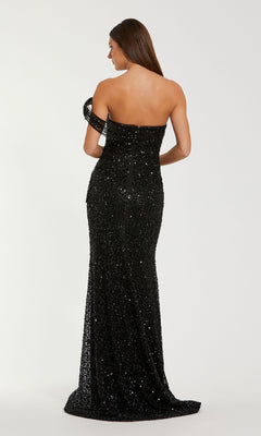A woman stands facing away from the camera against a plain background, wearing the Mac Duggal 37085 long formal dress—a floor-length black sequin gown with off-the-shoulder sleeves.
