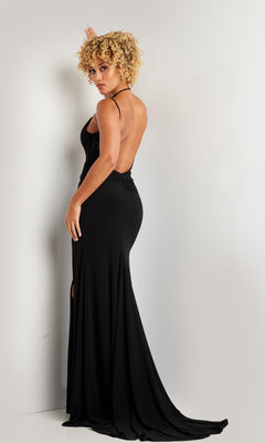 A person with curly blonde hair wears the Long Prom Dress 37086 by Jovani, a black open back gown with thin straps, standing against a white wall and looking over their shoulder.