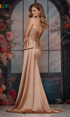 Wearing the Bow-Waist Long Satin Prom Dress: Colors Dress 3709, a woman poses before a floral arched window backdrop, showcasing its dramatic bow and train—an elegant pick for formal occasions.