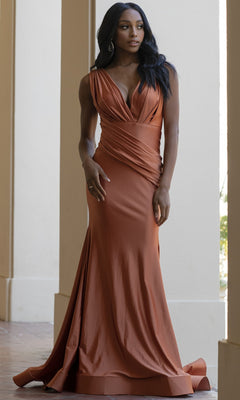 Woman in an Amelia Couture 370 Plunging V-Neck Long Lycra Prom Dress, sleeveless, floor-length mermaid style in rust with draped detailing, standing before columns.