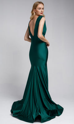 A woman poses against a plain light gray background wearing the Plunging V-Neck Long Lycra Prom Dress: Amelia Couture 370, a floor-length deep green mermaid gown with a low back and slight train.