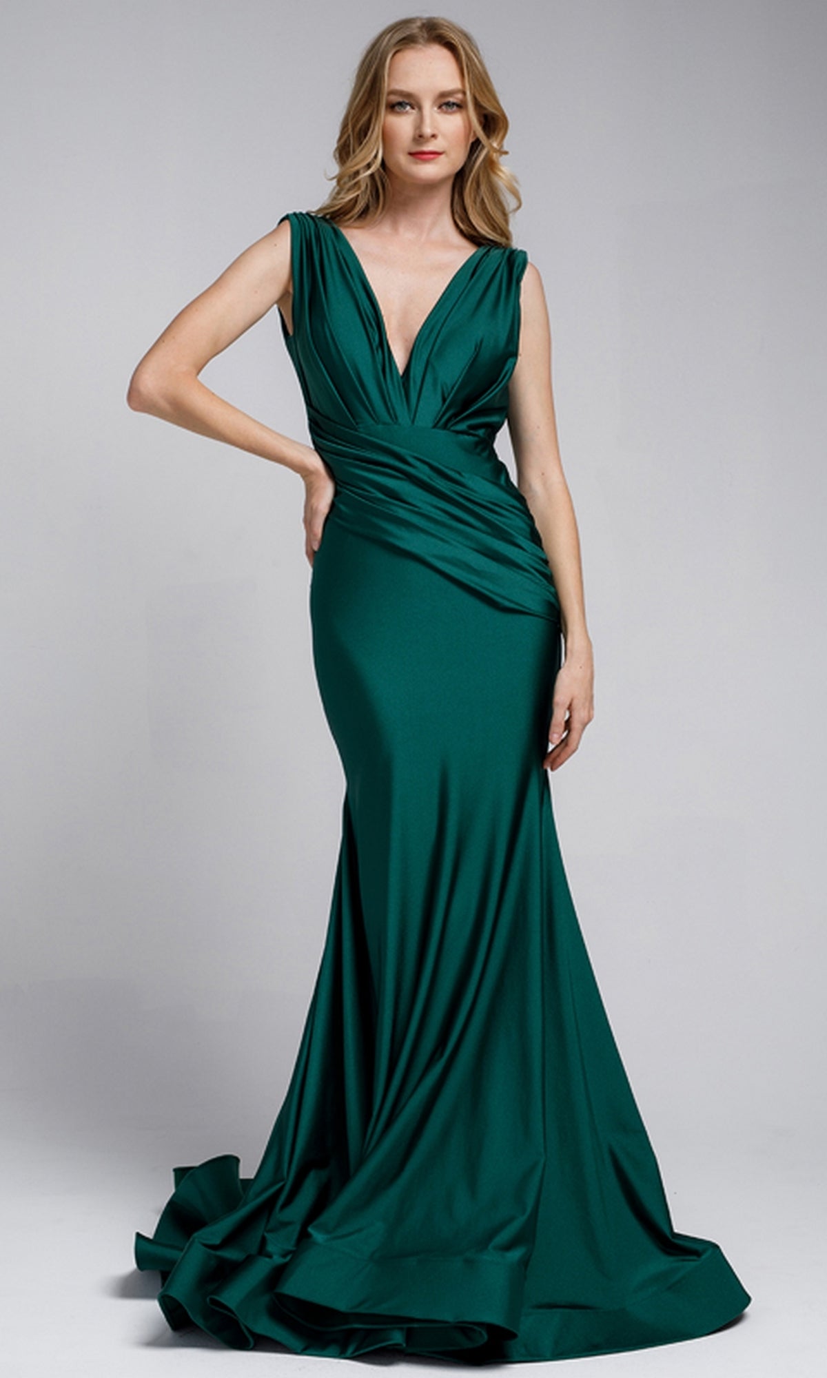 A woman in a plunging V-neck long lycra Amelia Couture 370 prom dress stands against a plain background.