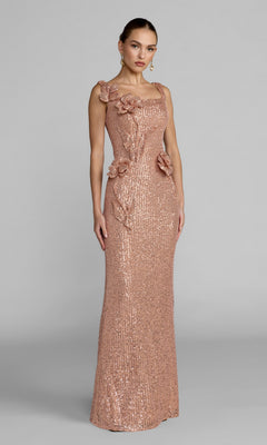 A woman wearing the Mac Duggal 37104 long formal dress in a fitted, sleeveless copper design with floral appliqués on the bodice and waist, posing against a plain gray background.