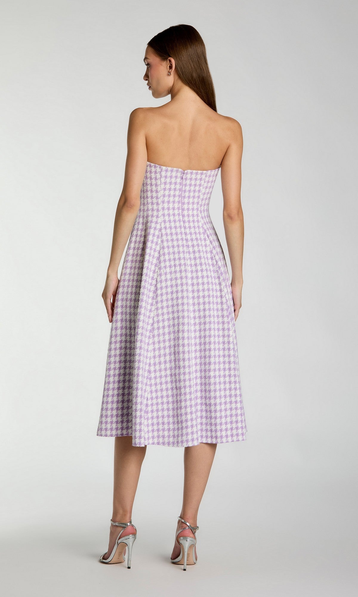 A woman wearing the Mac Duggal 37135 Strapless Gingham Midi Dress in lavender and white checks with high-heeled sandals, standing with her back to the camera.