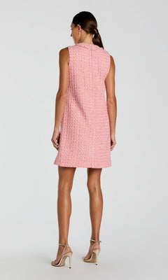 Woman standing, facing away, wearing the Mac Duggal 37136 Short Party Dress—a sleeveless pink textured mini dress crafted from boucle fabric—and beige high-heeled sandals, against a plain light background.