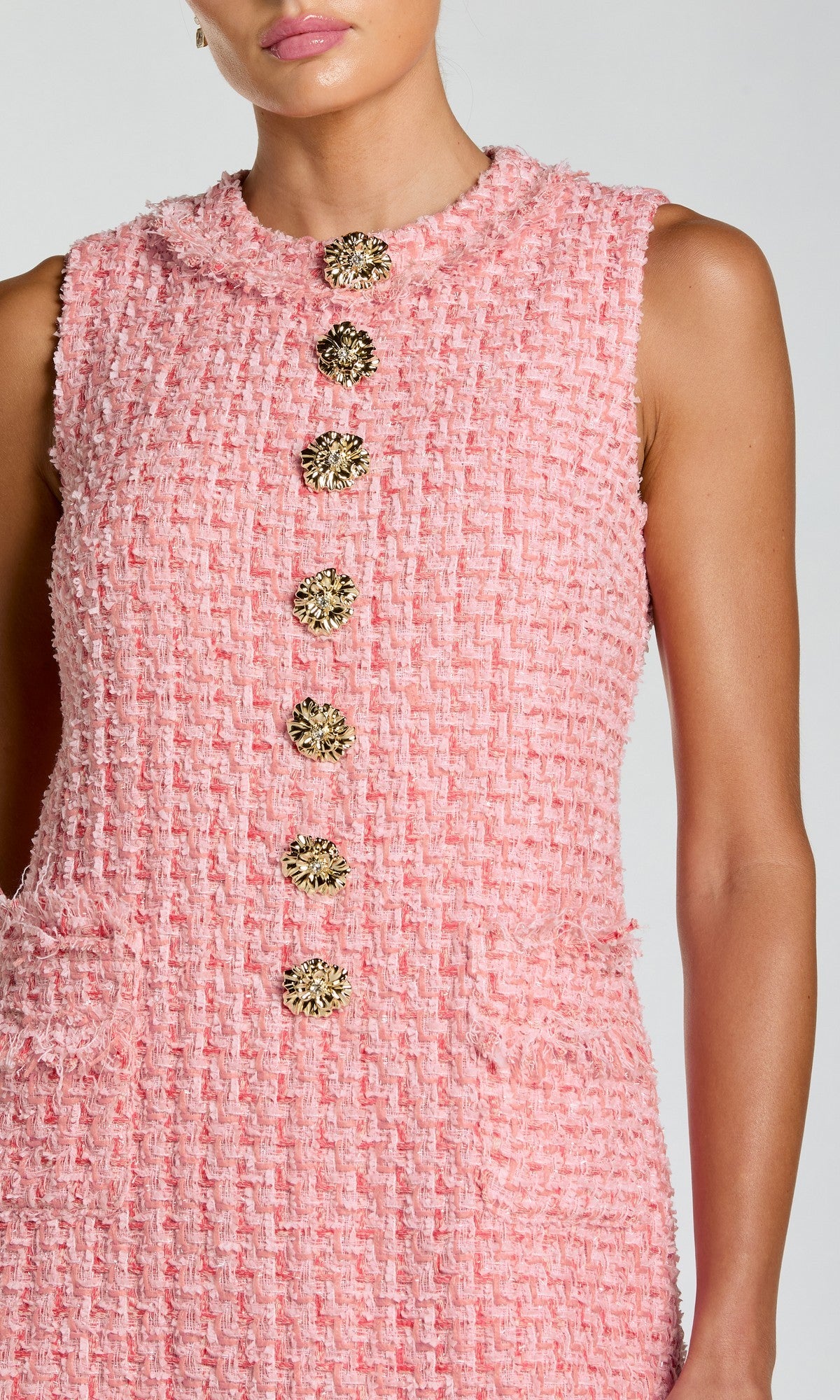 A woman models the Short Party Dress: Mac Duggal 37136—a chic sleeveless mini dress in pink boucle fabric, featuring large decorative gold buttons down the front and two front pockets. The photo shows her from shoulders to knees.