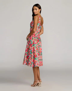 A woman wearing the Mac Duggal 37155 Floral Midi Wedding Guest Dress, featuring a sleeveless square neckline and floral print crepe fabric, paired with strappy high heels, stands in a studio with a neutral background.