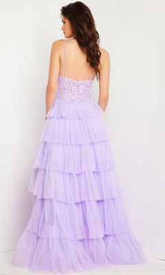 A woman faces away, wearing the Long Prom Dress 37190 by Jovani—a lavender ruffled tulle ball gown with a fitted, lace-embellished bodice and spaghetti straps—standing against a plain white background.