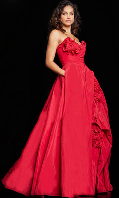 A woman stands against a black background in Jovani's Long Prom Dress 37266, a strapless, floor-length red ball gown featuring floral details and side pockets.