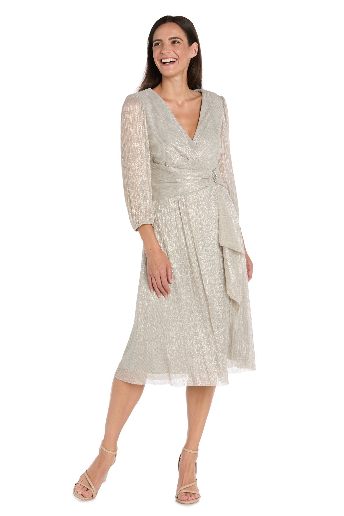 A woman smiles in the R&M Richards 3741 Metallic Knee-Length Party Dress, featuring silver fabric, long sleeves, and a V-neckline.