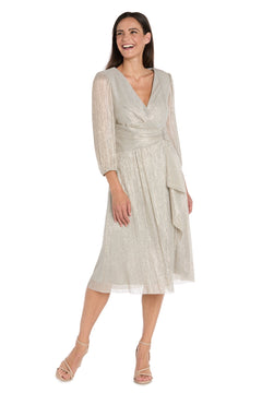 A woman smiles in the R&M Richards 3741 Metallic Knee-Length Party Dress, featuring silver fabric, long sleeves, and a V-neckline.