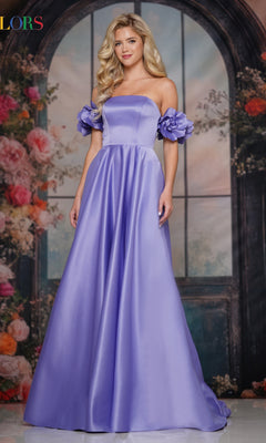 A woman in the Colors Dress Off-Shoulder Satin Prom Gown 3744 poses before a floral, arched window backdrop, highlighting the gown’s elegant and timeless style.