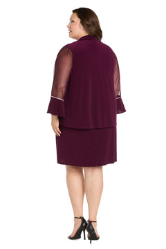 A woman in the Short Plus-Size Jacket Party Dress (R&M Richards 3747W), featuring sheer sleeves and ruffle cuffs, faces away from the camera. She finishes her look with black high-heeled sandals.