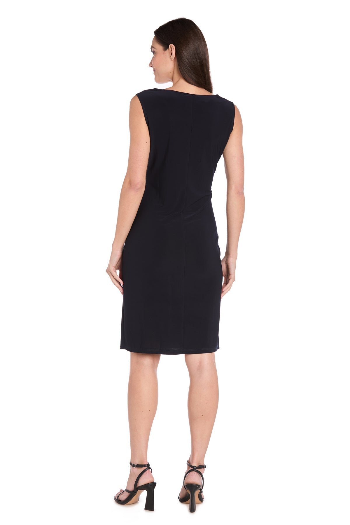 A woman faces away, highlighting the R&M Richards 3747P petite two-piece party dress—sleeveless, black, knee-length—paired with black high-heeled sandals against a white backdrop.