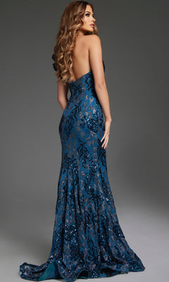 A woman stands against a plain background, looking over her shoulder in the Jovani 37634—a long, blue sequin prom dress featuring a backless design, floral pattern, and mermaid silhouette.