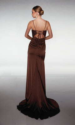 A woman wearing the Aerie Couture 376 long prom dress, in brown satin with thin straps and a lace-up back, stands with her back to the camera against a plain background.