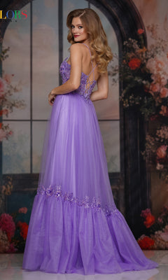 A woman in the Colors Dress 3799, a long lavender prom gown with a sheer embroidered bodice, lace-up open back, and floral embellishments, poses sideways among flowers before a large arched window.