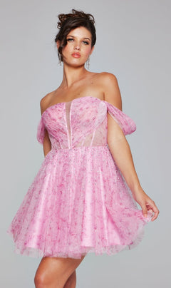 A woman stands against a gray background wearing the Jovani Off-Shoulder Short Pink Hoco Dress 38000, featuring sheer pink fabric and decorative embellishments.