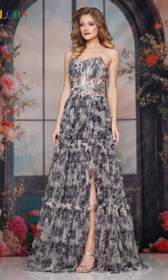 A woman stands before a floral backdrop in the Strapless Long Print Prom Dress: Colors Dress 3810, featuring a strapless design, front slit, and paired with silver strappy heels.