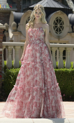 A woman smiles outdoors in the Strapless Long Print Prom Dress: Colors Dress 3810, her long blonde hair flowing. Architectural accents and greenery create a beautiful backdrop for this elegant evening gown.