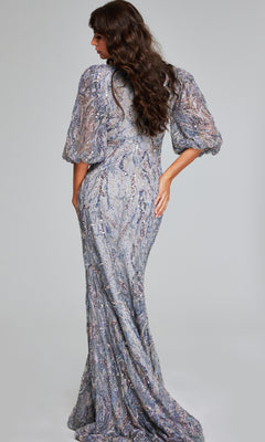 A woman with long wavy hair faces away, hand on hip, wearing the Jovani 38110 Long Grey Formal Dress adorned with sparkly embellishments.