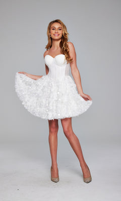 A woman stands smiling in the Jovani Strapless Short White Hoco Dress 38248, featuring a corset-style bodice and textured short skirt, paired with nude heels against a plain gray background.