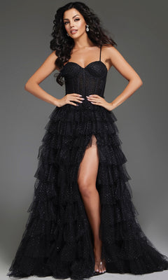 A woman models the Tiered Ruffle Black Prom Ball Gown, Jovani 38278, featuring a strapless corset bodice, ruffled ball-gown skirt, and thigh-high slit, against a plain gray background.