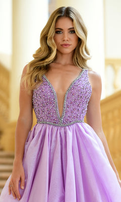 A woman wears the Ava Presley 38342 Deep V-Neck Long Prom Ball Gown in lilac, adorned with pearls, standing indoors with a staircase and columns behind her.