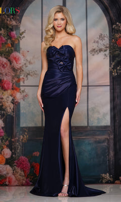 A woman wearing the Bow-Front Strapless Prom Gown (Colors Dress 3840) in navy, featuring a thigh-high slit, stands before a floral backdrop with arched windows.