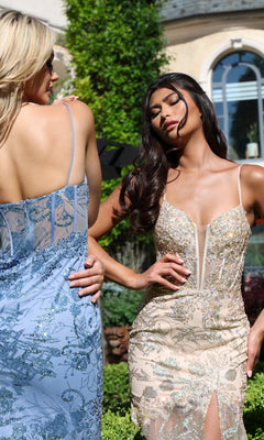 Two women stand outdoors in sunlight near lush greenery and an arched-windowed building, each wearing a fitted, sleeveless Jovani 38468 Illusion Long Sequin Prom Dress in champagne. The dresses feature intricate sequin detailing and floral embroidery, radiating elegance and charm—perfect for special occasions.