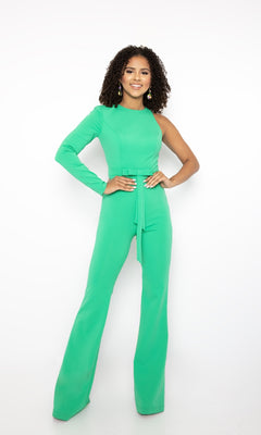 Model poses against a white background wearing the Long Formal Jumpsuit 38554 by Ava Presley in bright green, featuring one long sleeve and a round neckline, hands on hips and smiling at the camera.
