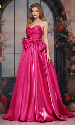 A woman stands indoors before a floral arched window backdrop, wearing the Lace-Up Strapless Prom Ball Gown: Colors Dress 3860 in hot pink satin with a large waist bow.