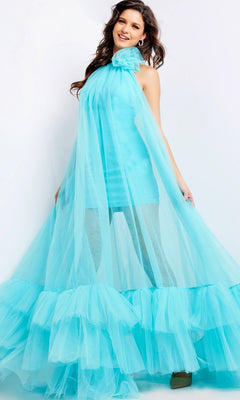 A woman wears the Long Prom Dress 38720 by Jovani, featuring bright aqua blue tulle, a sheer flowing overlay, and a ruffled hem, standing against a plain white background.