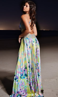 A woman stands on a beach at night, wearing the Long Prom Dress 38733 by Jovani—a colorful, flowing beaded strap dress with a floral pattern—looking over her shoulder with her hands on her hips.