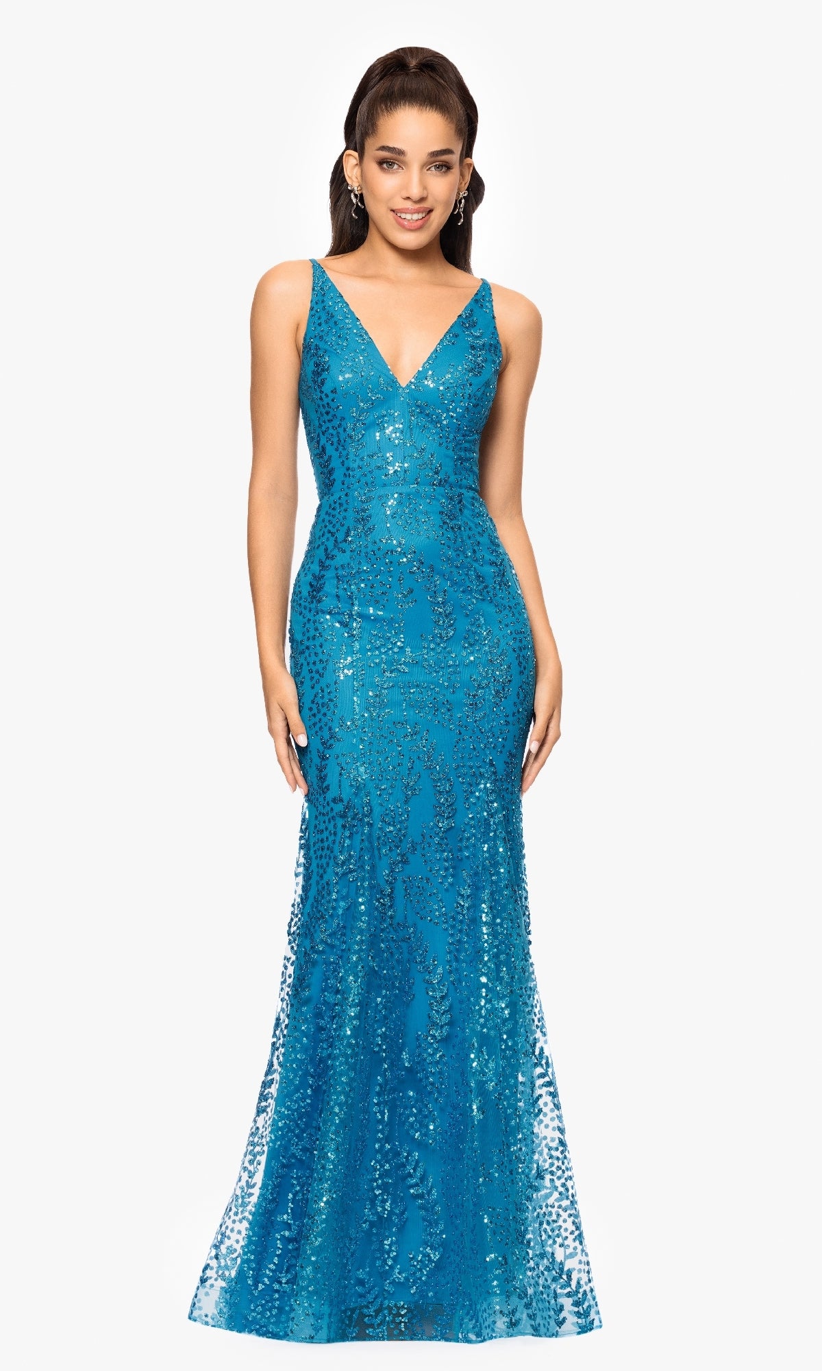 A woman stands against a plain white background wearing the Blondie Nites 3878BN long sequin-print prom dress, featuring a sleeveless design, floor-length cut, and V-neckline in blue.