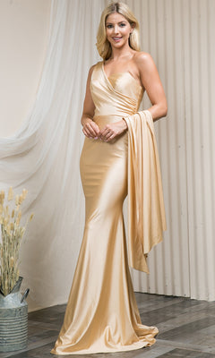 A woman stands indoors in old Hollywood style, wearing a champagne satin Side-Cape One-Shoulder Long Prom Dress 387 with a matching draped shawl. Nearby, dried flowers rest in a metal bucket.