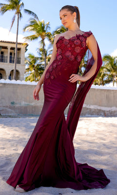 Woman posing on a sandy beach with palm trees and buildings behind her, wearing the One-Shoulder Long Formal Dress with Cape 388—a fitted, floor-length gown featuring a dramatic cape detail.