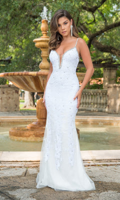 A woman stands before an outdoor fountain, wearing the Long Formal Dress 38813 by Ava Presley—a fitted, sleeveless white gown featuring beaded details, thin straps, and an embroidered corset bodice.