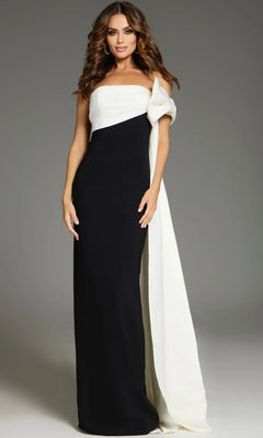 A woman stands against a plain gray background wearing the Jovani 38864 Long Formal Dress—a floor-length black gown featuring a white asymmetrical overlay and draped fabric detail over one shoulder.