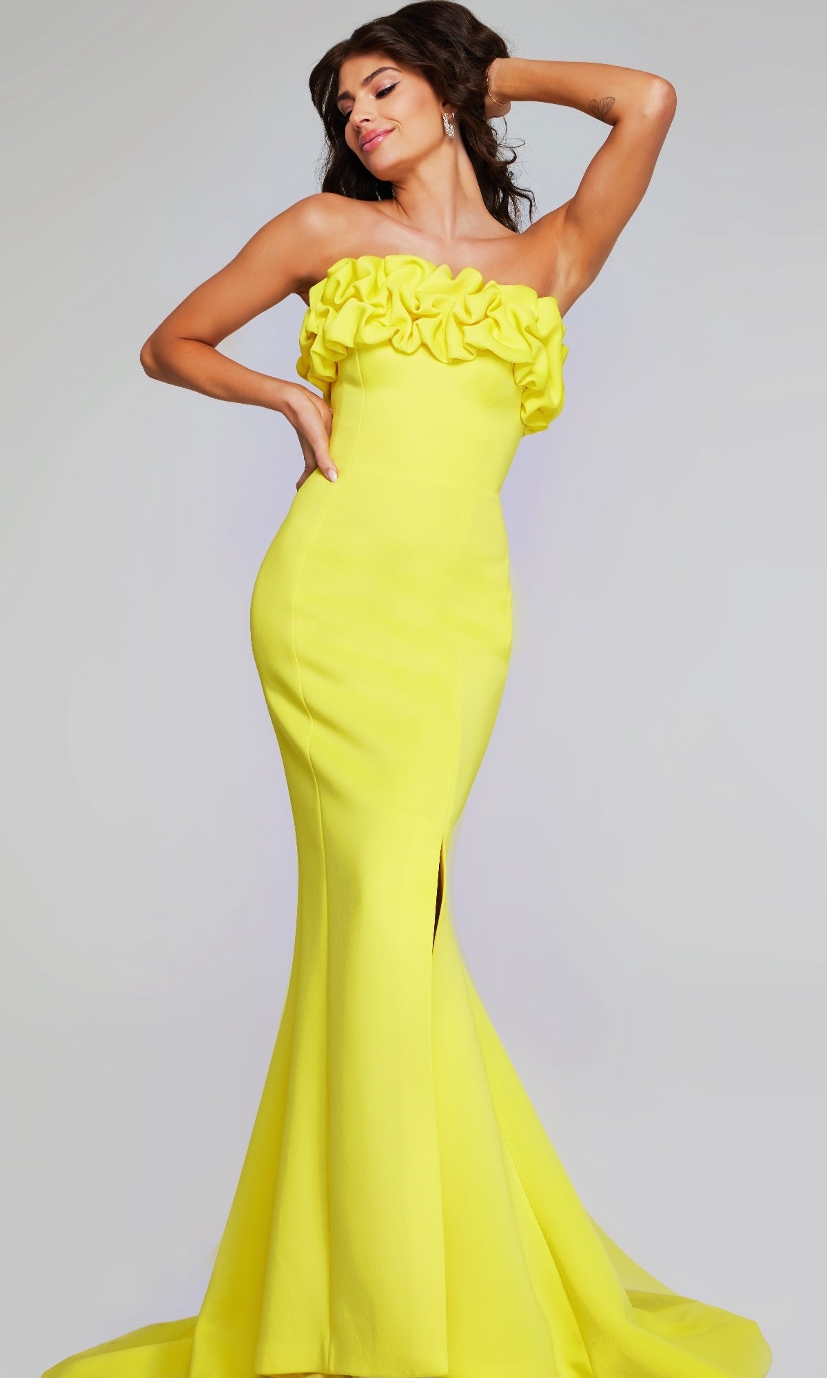 Woman poses in the Jovani 38922, a strapless floor-length yellow formal dress featuring ruffle detail across the chest and a front slit, with one hand on her hip and the other behind her head.