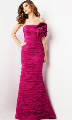 A woman poses elegantly against a plain white background, wearing the Long Formal Dress: Jovani 38947—a bright magenta, strapless, floor-length gown featuring textured horizontal pleats and a large flower accent on one shoulder.