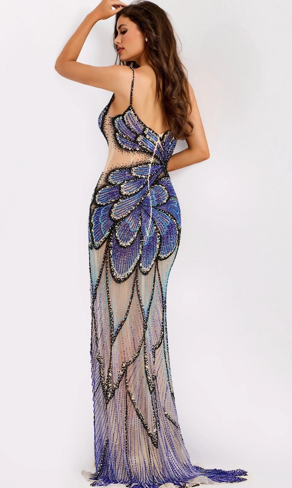 Woman wearing a fitted, floor-length gown with a sheer base and a dramatic butterfly-wing motif in large, blue and purple beading on the back.