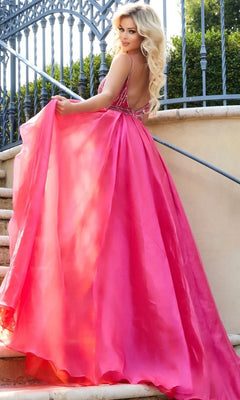 A woman with long blonde hair wears the Long Formal Dress: Jovani 39042, a backless bright pink gown, as she stands on outdoor stairs looking over her shoulder, with a wrought iron fence and greenery in the background.